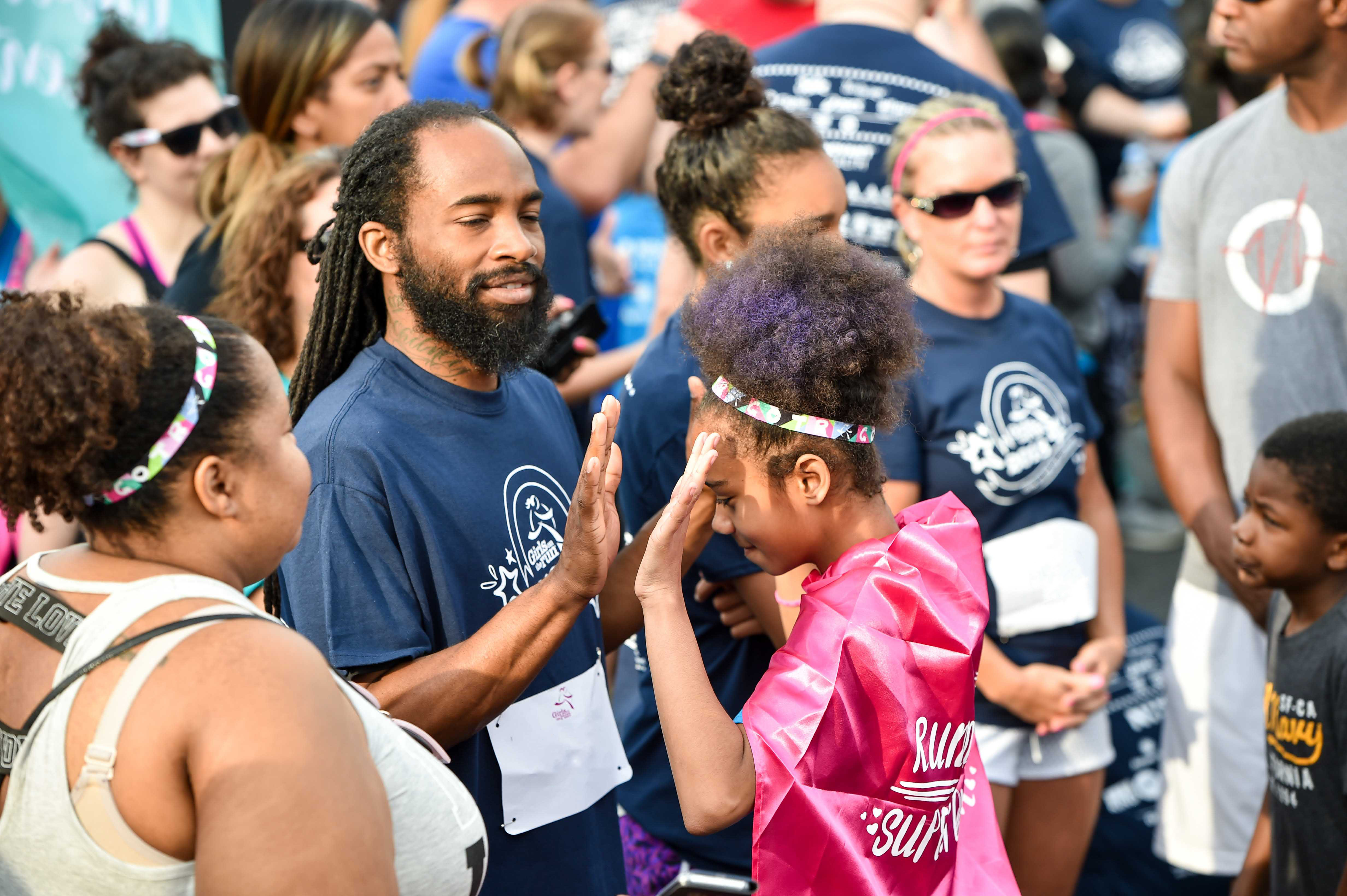 Girls on the Run participant high fives running buddy at 5K